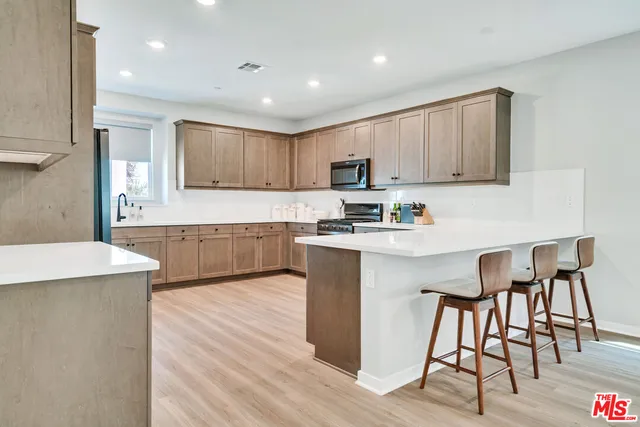 a kitchen with a table chairs a sink and a stove top oven with wooden floor