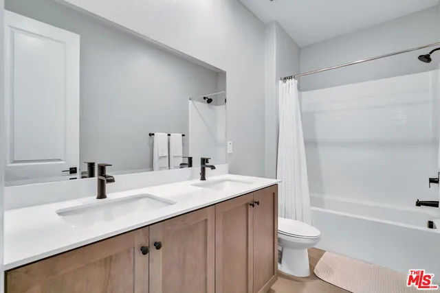 a bathroom with a sink a toilet a large mirror and shower