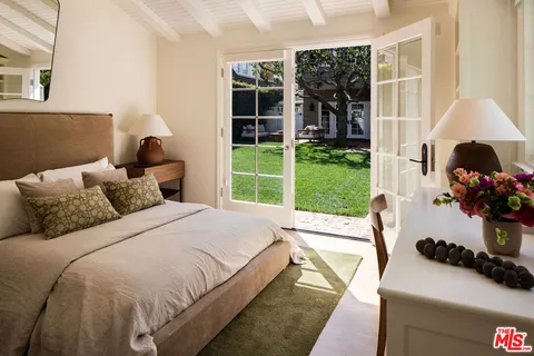 a bed sitting in a bedroom next to a window with potted plants