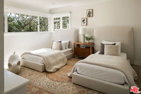 a bedroom with two beds and a large window