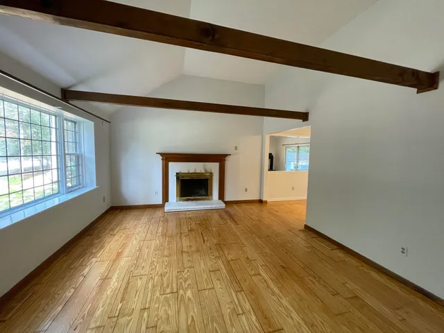 a view of an empty room with a fireplace and a window