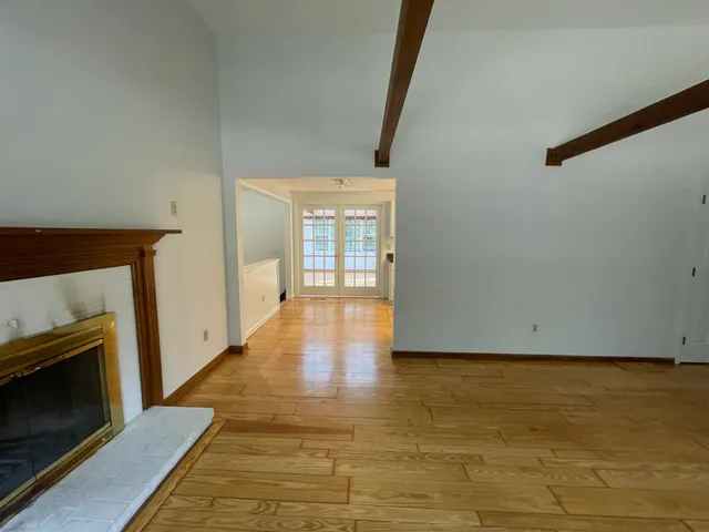 a view of an empty room with wooden floor and a fireplace