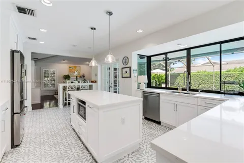 a large kitchen with kitchen island a large counter space a sink appliances and a large window