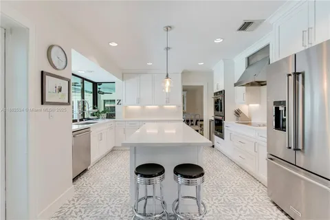 a large white kitchen with lots of counter space and stainless steel appliances
