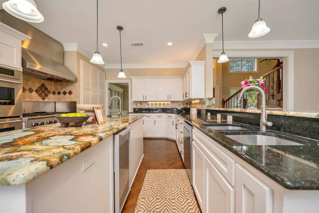 4008 Ramsgate Court Colleyville, TX 76034 - Photo 8 of 33 Gourmet kitchen featuring a large central island with exotic stone countertops, stainless steel appliances including a professional-grade range and built-in oven, white cabinetry, and a dark stone countertop with dual undermount sinks