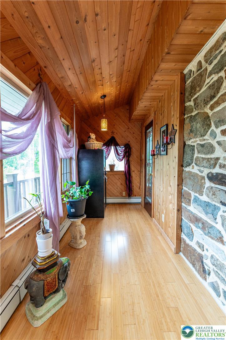 2485 Hieter Road Quakertown, PA 18951 - Photo 36 of 97 A rustic sunroom features exposed wood ceilings and floors, complemented by a natural stone accent wall.