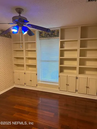 an empty room with wooden floor closet and windows