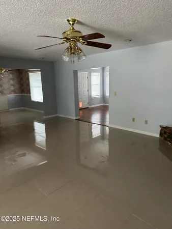 an empty room with windows and chandelier fan