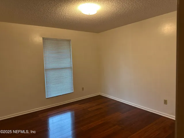 an empty room with wooden floor closet and windows