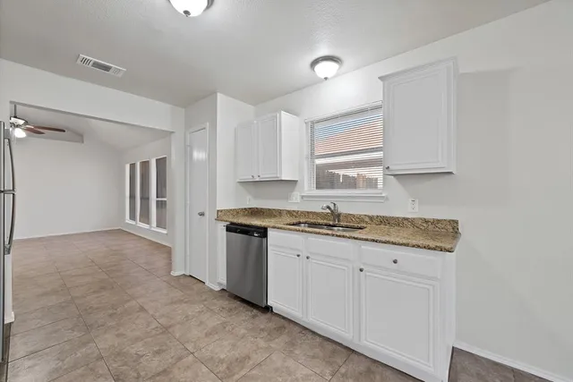a kitchen with granite countertop a sink a stove a refrigerator and cabinets
