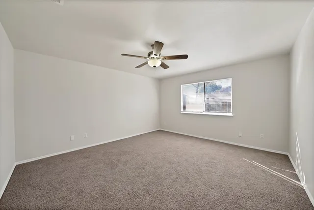 an empty room with a ceiling fan and a window