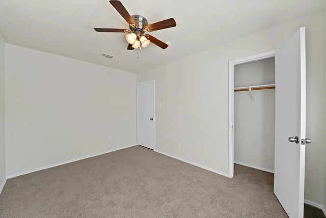 an empty room with a ceiling fan and a window
