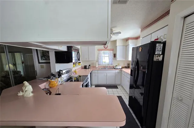 a view of kitchen with kitchen island wooden cabinets and refrigerator