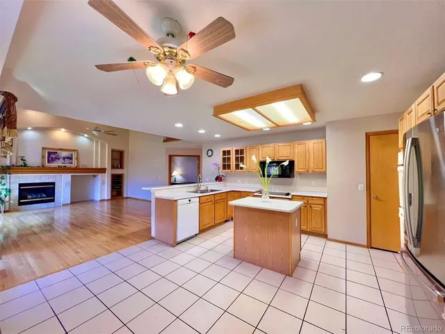 a kitchen with stainless steel appliances kitchen island granite countertop a refrigerator a stove top oven and a sink with granite countertops