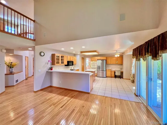a large living room with stainless steel appliances kitchen view and wooden floor