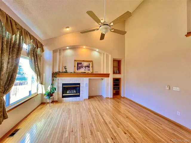 an empty room with wooden floor a fireplace and windows