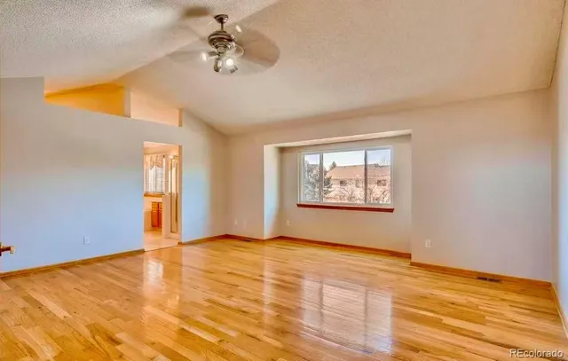 a view of an empty room with window and wooden floor