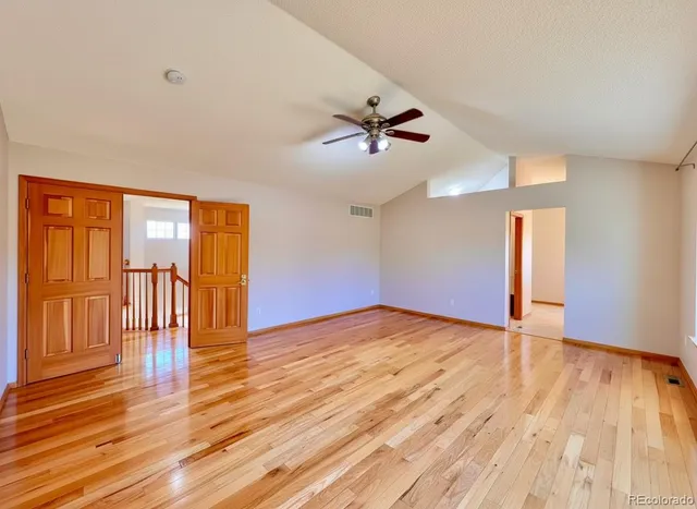 a view of empty room with wooden floor and fan