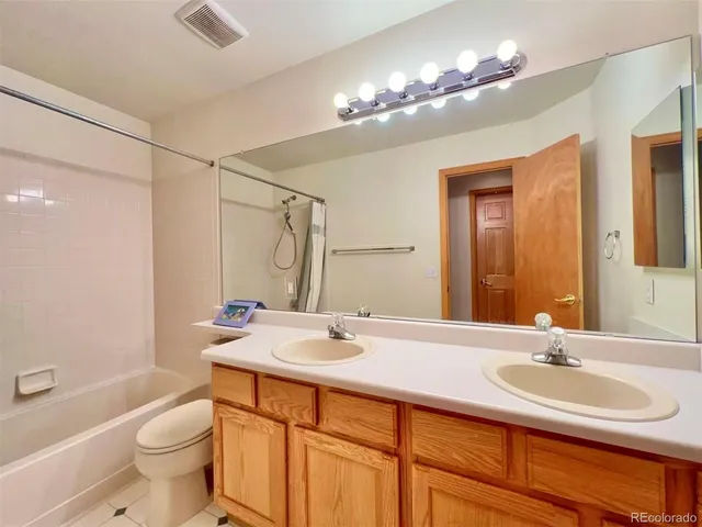 a bathroom with a double vanity sink toilet and a mirror