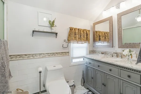 a bathroom with a granite countertop toilet sink and mirror