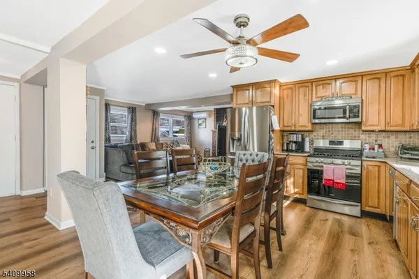 a open kitchen with stainless steel appliances granite countertop a stove a refrigerator a kitchen island a dining table and chairs with wooden floor