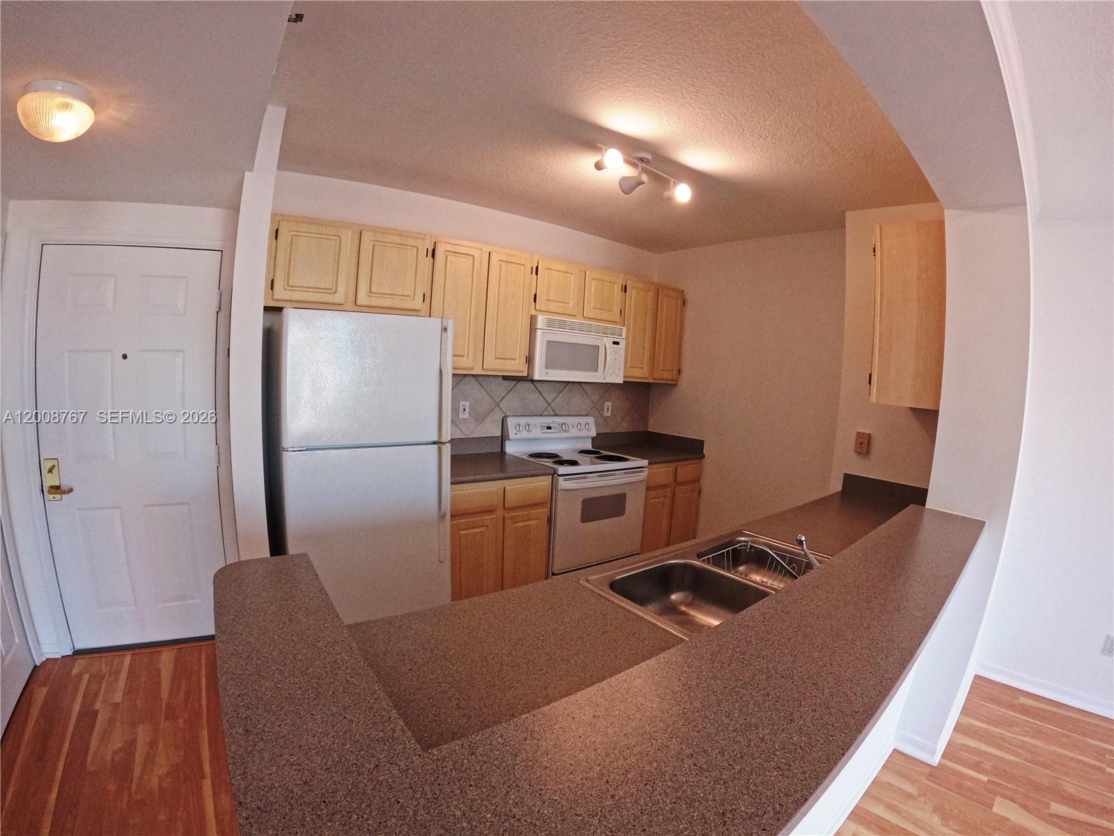 2665 Southwest 37th Avenue, Unit 710 Miami, FL 33133 - Photo 2 of 13 a kitchen with refrigerator cabinets and wooden floor