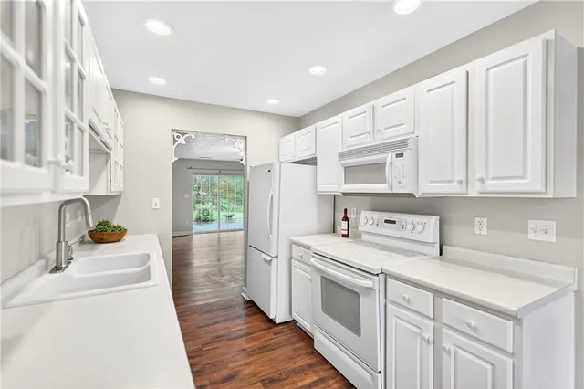 a kitchen that has a lot of white cabinets and wooden floor