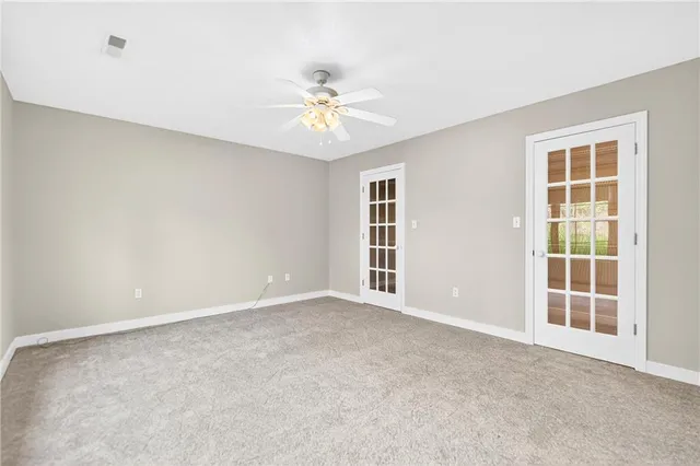 an empty room with windows and chandelier fan