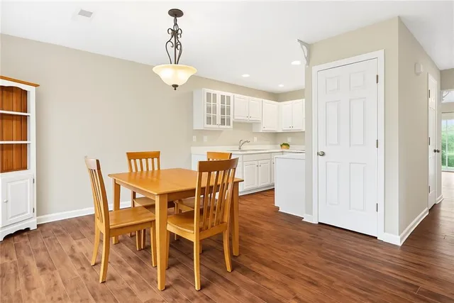 a dining room with wooden floor a chandelier a wooden table and chairs