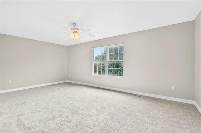 an empty room with a window and ceiling fan