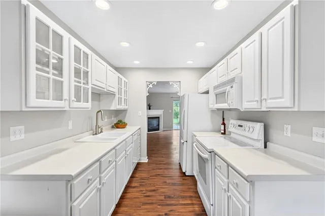 a kitchen that has a lot of white cabinets and wooden floor