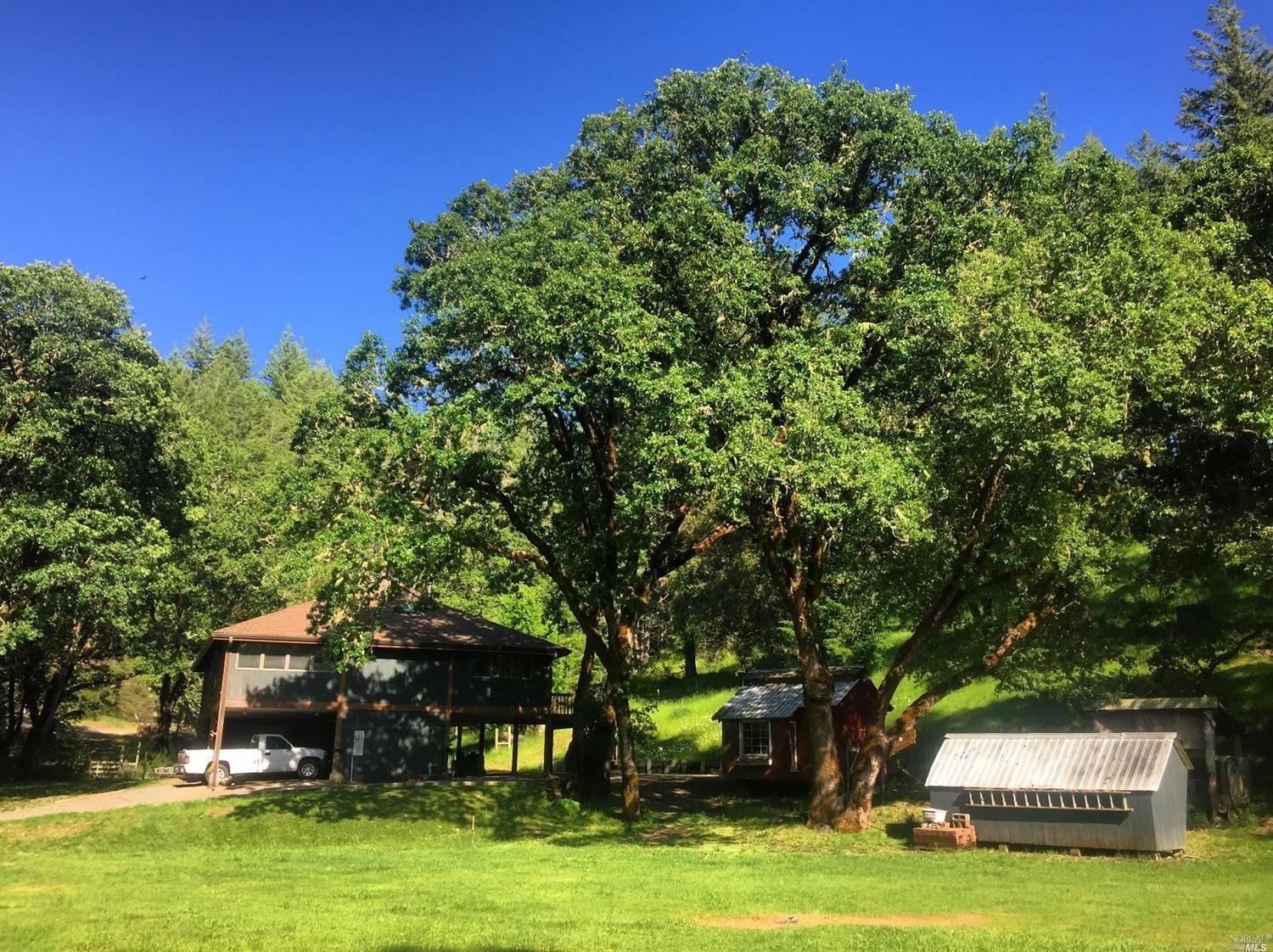 3951 Muir Mill Road Willits, CA 95490 - Photo 1 of 1 a front view of a house with a garden and trees