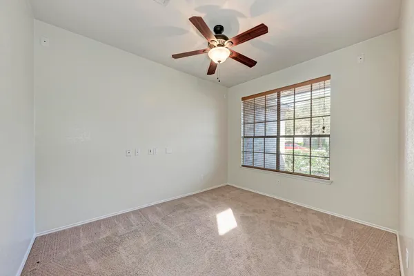 an empty room with ceiling fan and windows