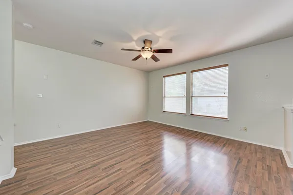 an empty room with wooden floor and ceiling fan