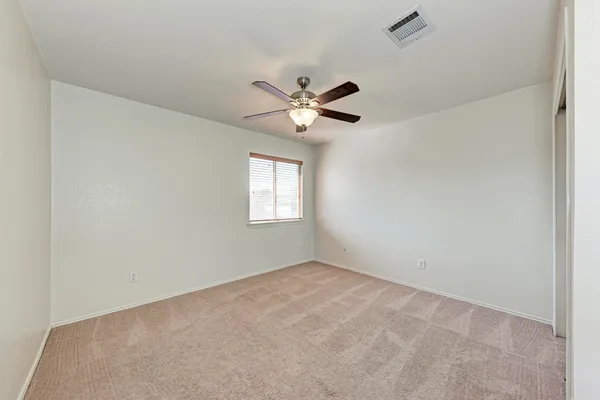an empty room with windows and a chandelier fan