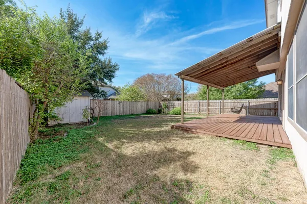 a backyard of a house with plants and trees with wooden fence