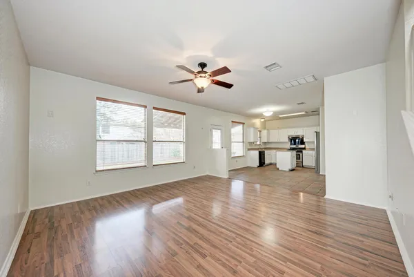 a view of an empty room with window and wooden floor