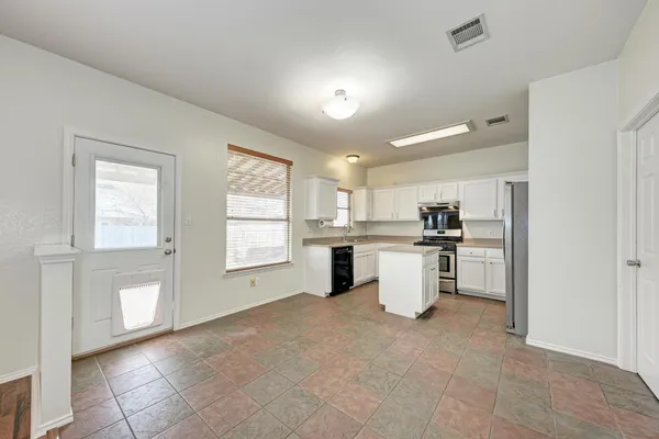 a kitchen with a refrigerator and white cabinets