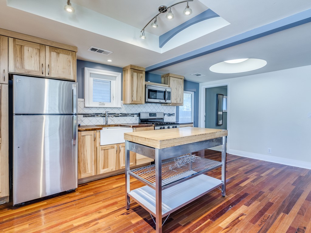 2314 Santa Rosa Street Austin, TX 78702 - Photo 3 of 27 Kitchen with stainless steel appliances, light wood finish cabinetry, tasteful backsplash, wooden counters, and a raised ceiling