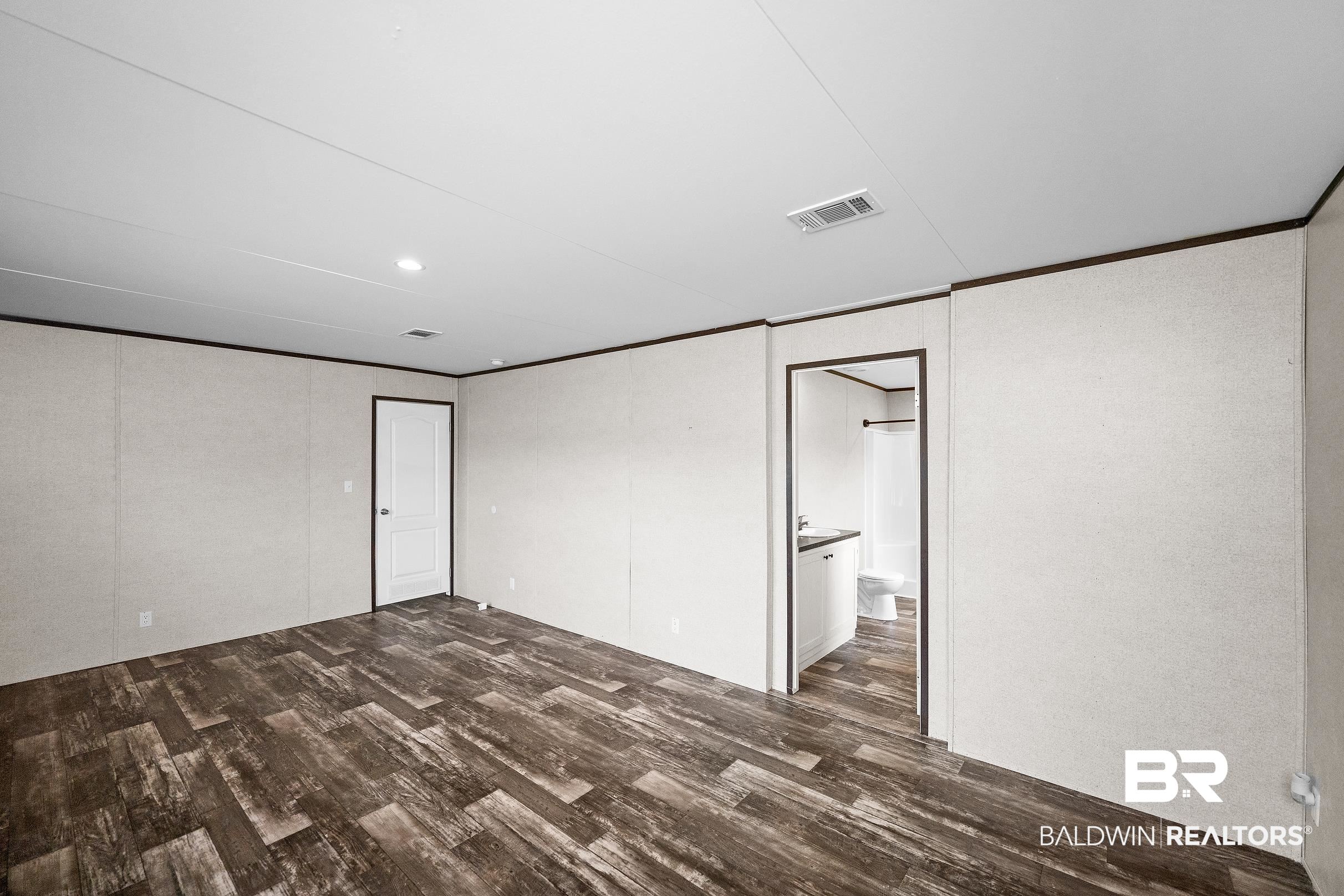 21601 Westside Loop Silverhill, AL 36576 - Photo 21 of 42 Spacious room featuring wood-finish flooring, light-toned walls with dark trim, and a ceiling with recessed lighting and a ventilation grate