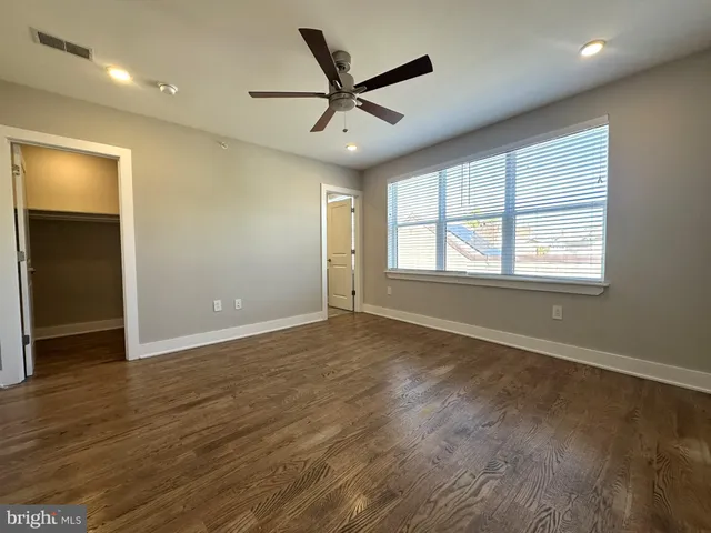 an empty room with wooden floor and a ceiling fan