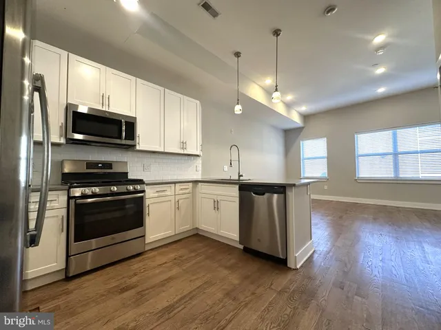 a kitchen with stainless steel appliances granite countertop a stove a sink and a microwave