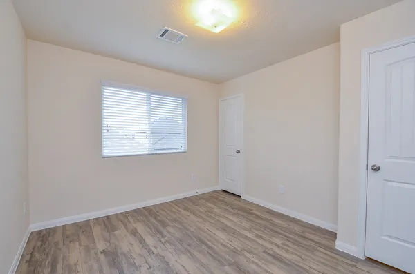 an empty room with wooden floor and windows