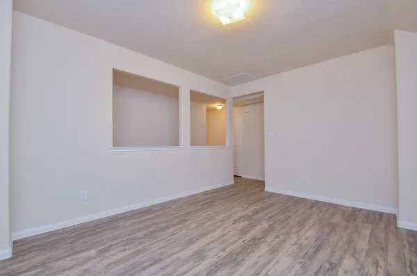 a view of an empty room with wooden floor and a window