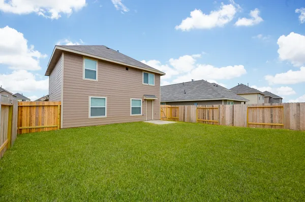 a view of a yard in front of a house with plants and wooden fence