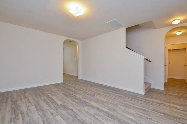 a view of an empty room with wooden floor and a window