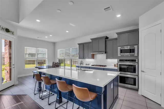 a kitchen with kitchen island granite countertop a stove a sink a dining table and chairs