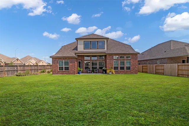 a view of a big house with a big yard and large trees