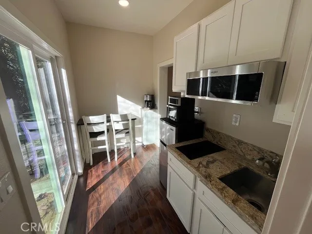 a kitchen with granite countertop a refrigerator a stove a microwave and furniture