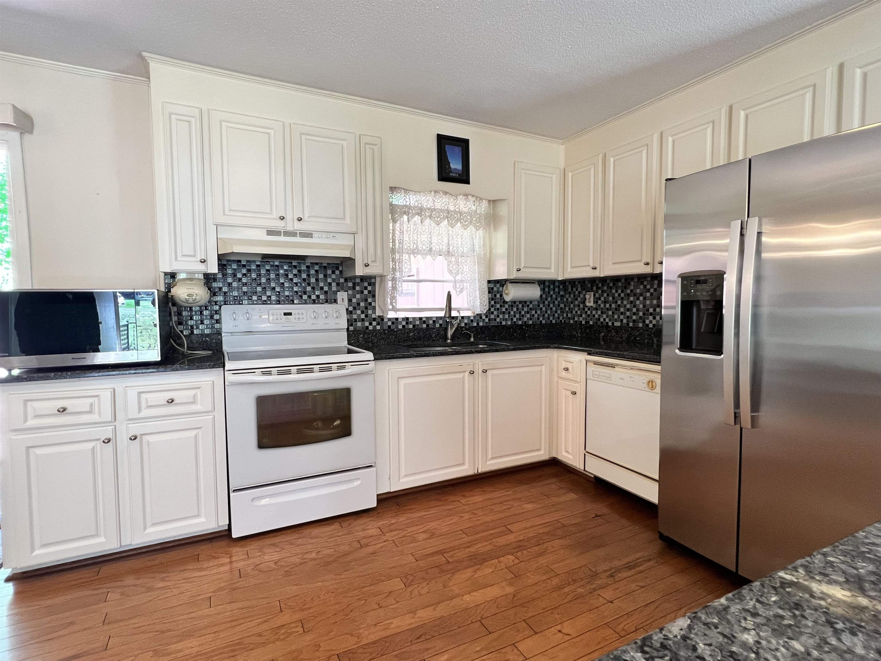 624 Woodland Road Raleigh, NC 27603 - Photo 11 of 29 a white kitchen with sink a refrigerator and white cabinets